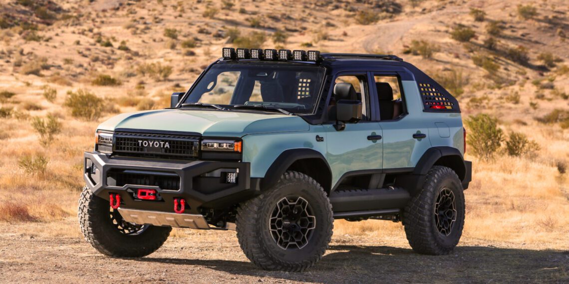 The 2024 SEMA-ready Toyota is a rugged off-road vehicle boasting a striking blue and black exterior. Parked on a dirt path in the dry, hilly landscape, it features roof lights and large tires, perfect for any adventure concept you can imagine.