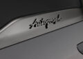 Close-up of a vehicle with "Autograph" logo on a sleek surface, featuring a partial taillight. The design echoes the elegance of an Infiniti, blending tailgating luxury with sophistication reminiscent of the AUTOGRAPH Lounge.