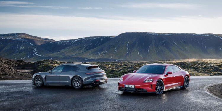 Two sleek Taycan 4 cars are parked on a wet road in a mountainous landscape under a cloudy sky.