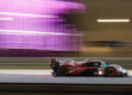 A Porsche race car speeds along the track at night, with motion blur capturing the vibrant pink lights in the background, setting the stage for an exhilarating 2024 FIA WEC season.