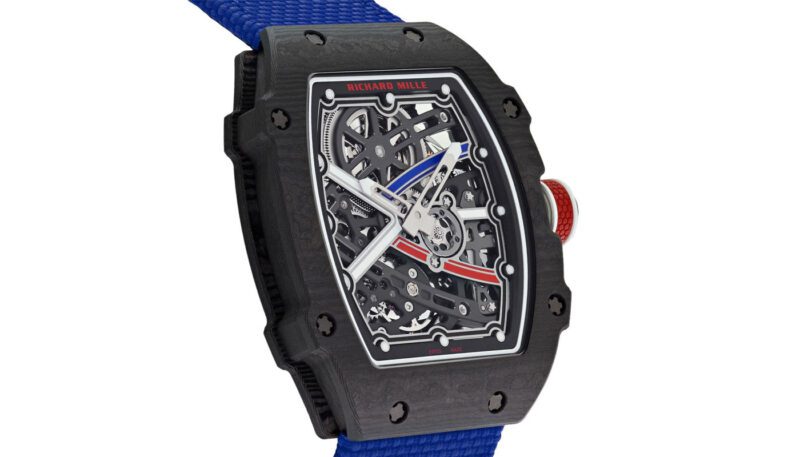 A luxury timepiece showcased in a black case with an openwork dial and a striking blue strap. Silver-toned hour and minute hands pair elegantly with red and blue accents on the face, as well as a bold red crown. Discover more at the exclusive Watch Auction by Kodner Galleries.