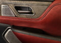 Close-up of an Infiniti car door interior featuring red leather upholstery, a silver Klipsch speaker, and a chrome door handle with a paneled wood design—a true touch of tailgating luxury.