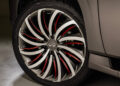 Close-up of an Infiniti car wheel showcasing a distinctive spiral spoke design with silver and red accents, epitomizing tailgating luxury. The Falken tire is seamlessly mounted on the metallic gray vehicle, highlighting elegance and precision.