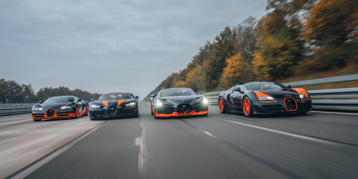 Four Bugatti sports cars, including the renowned W16 Mistral, drive side by side on a highway. Trees line the road under an overcast sky as these high-performance machines hint at their speed record potential.