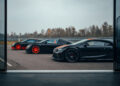 Three sleek black Bugatti sports cars with vibrant red accents are parked on a paved area near a racetrack on a cloudy day, hinting at their open-top speed record capabilities with the prowess of the W16 Mistral engine.