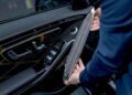 A person expertly installs a speaker panel on a car door interior, adding a touch of customization that reflects the precision and luxury synonymous with Mercedes-Benz and MANUFAKTUR Studio craftsmanship.
