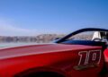 Close-up of a Mercedes-AMG red convertible sports car with the number 10, parked by a calm lake with mountains in the background under a clear blue sky, PureSpeed revealed in every detail.