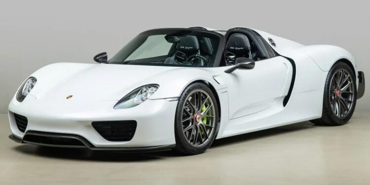 A white Porsche 918 Spyder with a sleek design, two doors, and black accents, parked on a smooth surface.