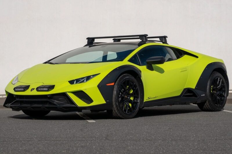 A bright yellow Lamborghini Huracán Sterrato sports car with a sleek design and black accents, parked on a paved surface. It features a roof rack and distinctive headlights, embodying adventure. .