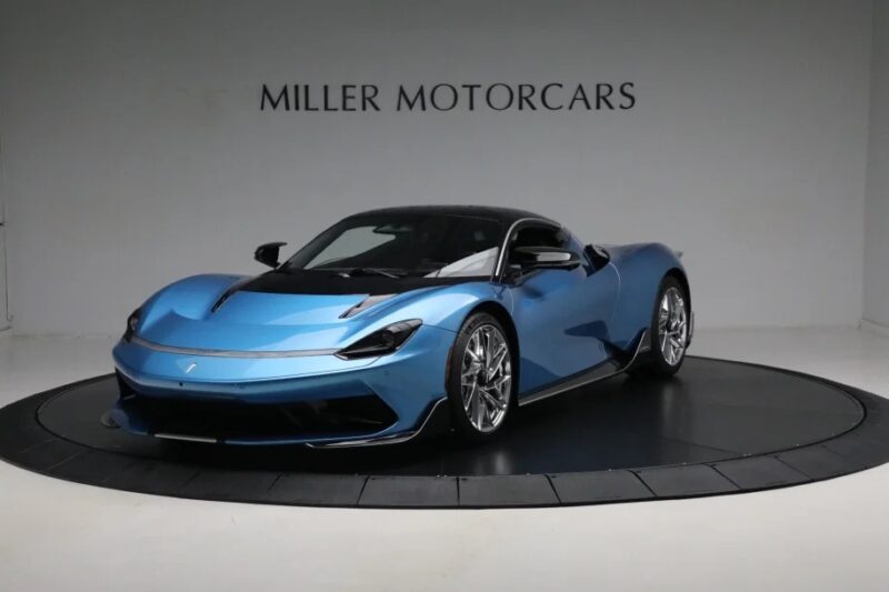 A sleek blue electric hypercar, the Pininfarina Battista, is on display in the showroom with "Miller Motorcars" proudly showcased on the wall behind it. This stunning vehicle is for sale, capturing attention with its innovative design and engineering excellence.