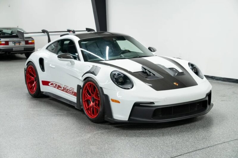 The ultimate driver's car, a Porsche 911 GT3 RS with red wheels and black accents, is parked indoors.