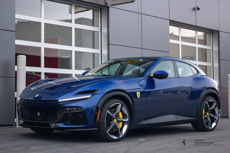 SUV Ferrari Purosangue biru yang menakjubkan diparkir di depan sebuah gedung. Ini menawarkan desain sporty dengan kaliper rem kuning yang menarik. Beli Ferrari hari ini untuk mengalami kemewahan dan kinerja yang tak tertandingi.