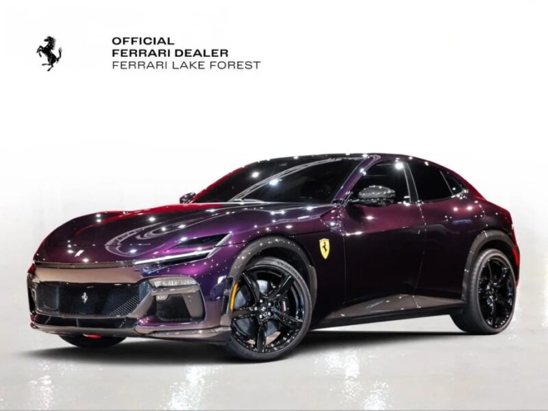 Ferrari Purosangue ungu dengan pelek hitam dipamerkan di showroom. Latar belakang menawarkan logo dan teks, menandainya sebagai dealer resmi, Ferrari Lake Forest. SUV langka ini sekarang tersedia untuk dijual kepada para penggemar yang cerdas.