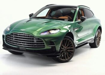 For sale: This green luxury Super-SUV, the Aston Martin DBX 707, boasts a sleek design with a large grille and dark tinted windows, all set against a pristine white background.