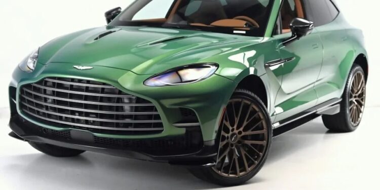 For sale: This green luxury Super-SUV, the Aston Martin DBX 707, boasts a sleek design with a large grille and dark tinted windows, all set against a pristine white background.