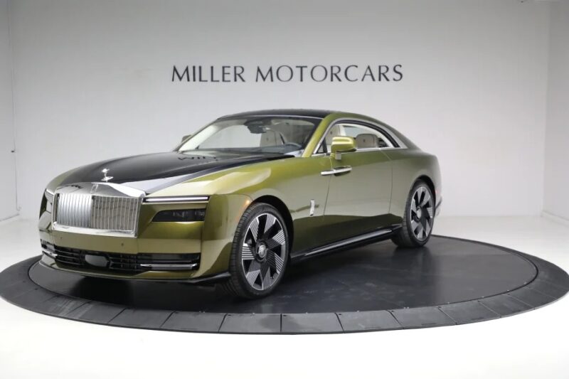 A luxury Electric Super Coupe with a two-tone green and black exterior is displayed on a rotating platform in a showroom labeled "Miller Motorcars.