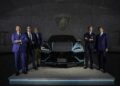 Five distinguished men in suits stand next to a sleek black Lamborghini Urus Performante, showcased on a lit platform with the iconic Lamborghini logo behind them, highlighting the exclusive Ad Personam Program.