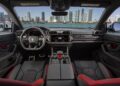 The interior of a Lamborghini Urus SE offers an unparalleled view, with sleek leather curves framing a vibrant city skyline and shimmering water through the windshield, embodying the luxury you'd expect during Art Basel 2024.