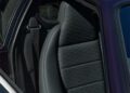 Close-up of a BMW M1's rear seat with black upholstery featuring a textured pattern, curated in collaboration with KITH. The seatbelt is visible on the left side.