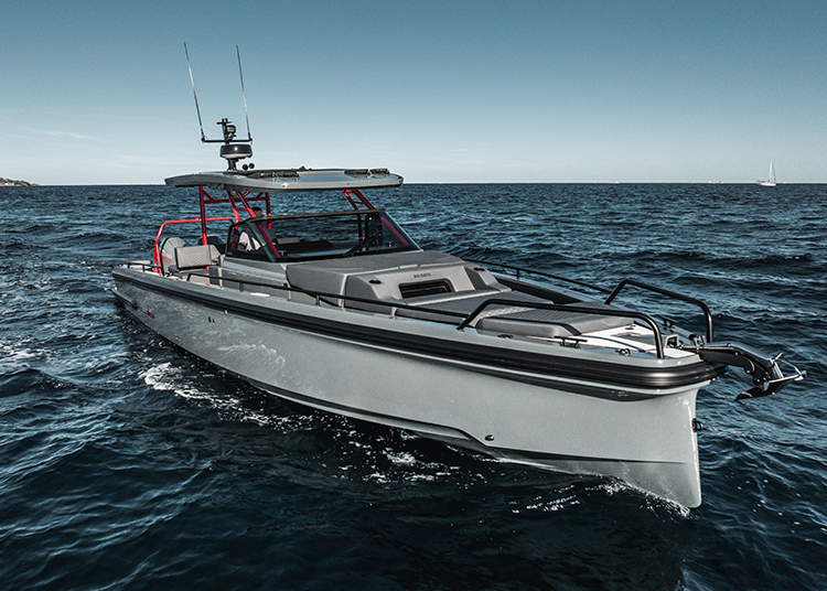 A sleek, modern motorboat with a gray hull and red accents, featured in the duPont REGISTRY's Holiday Gift Guide 2024, cruises on a calm sea under a clear sky.