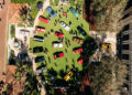 Aerial view of a car show on a circular grassy area with various colored cars displayed and people walking around.