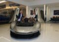 Two people stand beside an exotic Automobili Pininfarina with butterfly doors open inside the Braman Motorcars showroom, reminiscent of Palm Beach luxury.