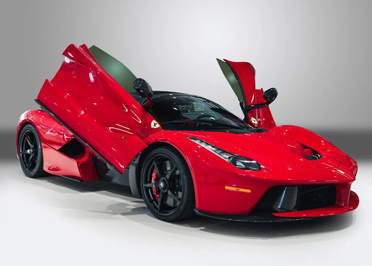 A sleek Ferrari LaFerrari with scissor doors open is on display in the showroom. This hypercar boasts black wheels and a stunning design, now available for sale to admirers of unparalleled performance and elegance.