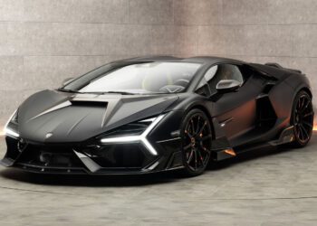 A sleek, black Mansory sports car with sharp angles parked in a modern, concrete-walled room.