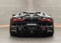 Rear view of a sleek, black custom Lamborghini Revuelto with distinctive tail lights and aerodynamic design, photographed indoors.