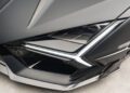 Close-up of a sleek, modern car's front headlight and grille, featuring sharp angles and carbon fiber details reminiscent of Mansory's custom Lamborghini designs.