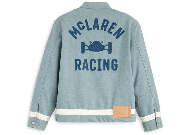 This light blue jacket, featured in the 2024 duPont REGISTRY Holiday Gift Guide, showcases "McLaren Racing" and a racing car graphic in dark blue on the back. White stripes near the cuffs and hem add a classic touch to this stylish piece.