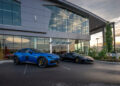 At sunset, two luxury sports cars gleam in front of a modern glass dealership building, reminiscent of a grand gala evening. The picturesque scene brings to mind the elegance often found at Make-A-Wish events in Middle Tennessee.