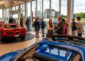 At the Middle Tennessee Gala, people converse at a car dealership event, surrounded by luxury cars. Indoors, natural light from large windows highlights a night where dreams come true.