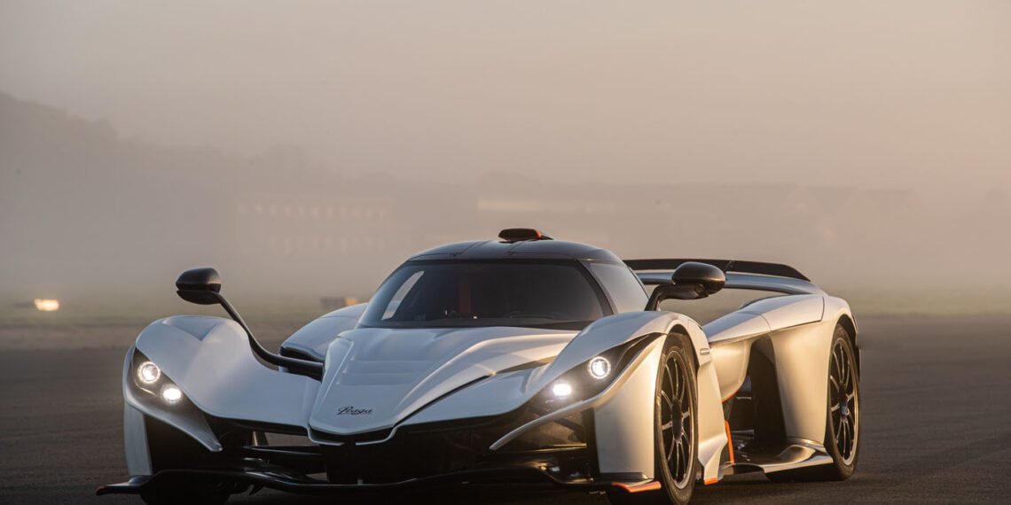 A sleek, white Praga sports car with aerodynamic design features is parked on a foggy road, exuding the allure of a supercar.