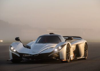 A sleek, white Praga sports car with aerodynamic design features is parked on a foggy road, exuding the allure of a supercar.
