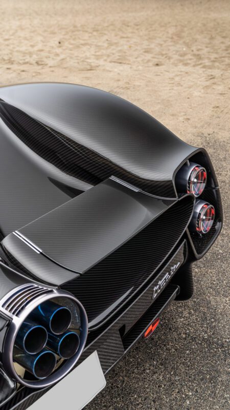 Close-up view of a sleek sports car's rear, featuring dual exhausts, taillights, and carbon fiber components.