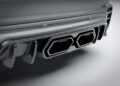 Close-up of a Rolls-Royce Cullinan's rear bumper showcasing dual exhaust pipes with a carbon fiber finish, reflecting exquisite Mansory customization.