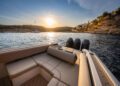 As the sun dips below the horizon, the view from the back of a Wajer Yacht reveals shimmering waters kissed by golden light, framed by hills and timeless design in distant buildings. A luxurious escape where nature's beauty meets exquisite craftsmanship.