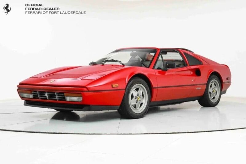 A red Ferrari 328 GTS sports car is displayed in a showroom, viewed from a three-quarter angle. The car embodies a sleek, low-profile design typical of classic Ferrari models, making it an enticing investment for those guided by data-driven insights.