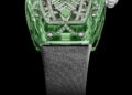 The RM 07-02 from Richard Mille’s Sapphire Collection is a luxury watch with a transparent green case, intricate silver and diamond detailing on the face, and a satin-like strap, set against a sleek black background.