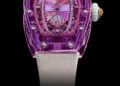 Experience the elegance of the RM 07-02 Sapphire by Richard Mille—a purple luxury watch with a transparent case. Its ornate dial, showcasing pink accents and gemstone details, is paired with a beige strap. This stunning piece embodies vibrant colors against a striking black background.