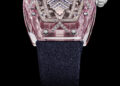 The RM 07-02 Sapphire luxury wristwatch dazzles with a diamond-encrusted face, vibrant colors of pink and clear casing, blue and silver detailing, all complemented by a dark strap. Set against a black background, this Richard Mille masterpiece captures elegance and sophistication.