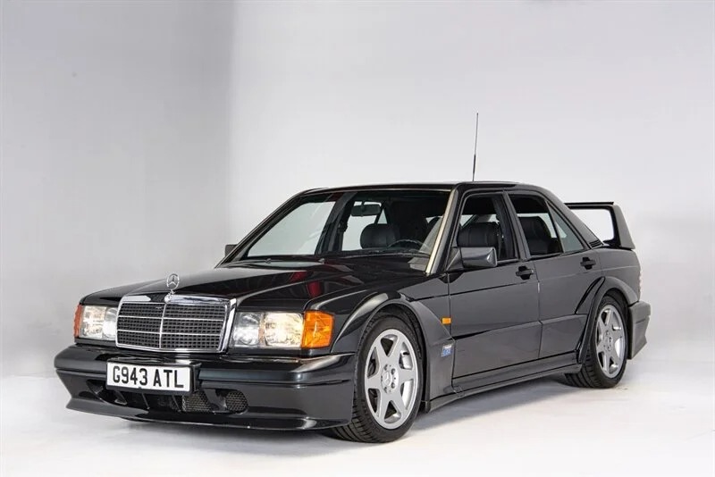 Black Mercedes-Benz sedan with a rear spoiler, low-profile tires, and UK license plate "G943 ATL," photographed in a studio with a plain white background—a classic piece of 90s cars for sale that brings nostalgia to any enthusiast.