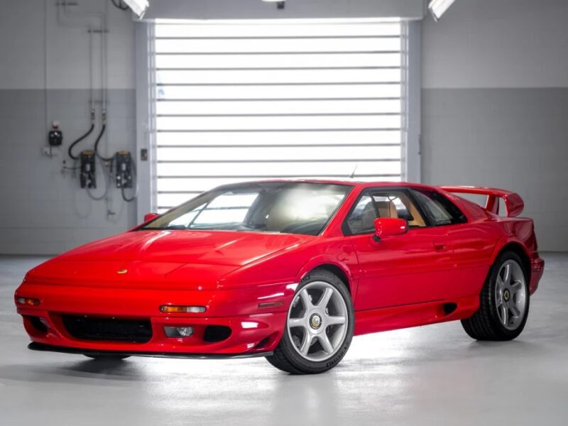 A luxury red sports car is elegantly parked indoors, showcasing its highlighted design details and chic spoiler, making it a stunning addition to any exotic car collection.