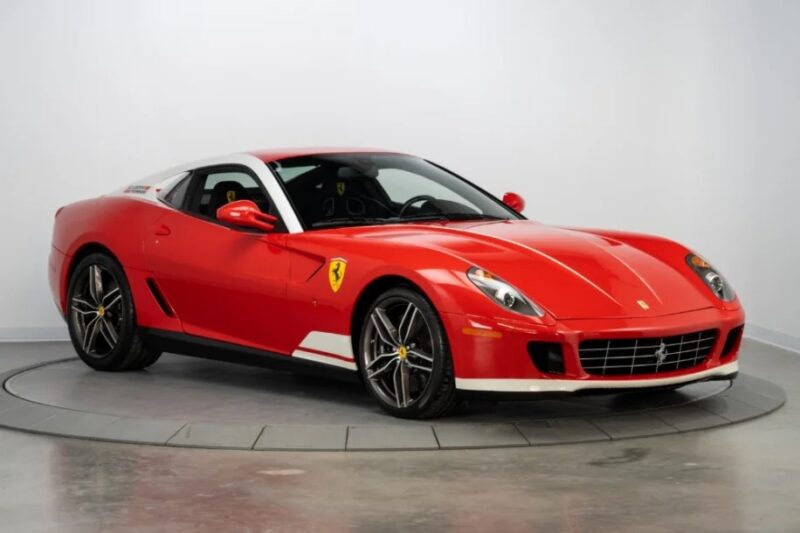 A red Ferrari sports car, powered by a formidable V12 engine, is on display in the showroom. This exotic car features a sleek design and alloy wheels, elegantly positioned on a rotating platform.