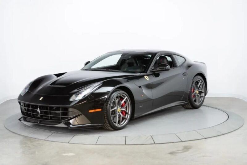 A sleek, black sports car is showcased in a studio setting, epitomizing the allure of exotic cars. Its modern design is accentuated by red brake calipers and distinctive alloy wheels.