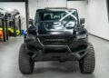 Front view of the majestic black Rezvani Hercules 6x6 truck in a garage, showcasing its sleek, angular design and robust off-road tires.