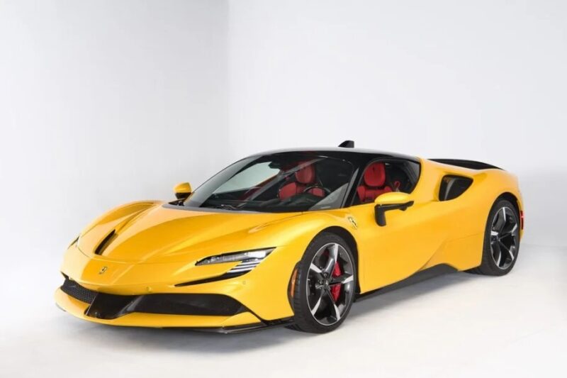 Yellow exotic sports car with red and black interior, featuring a sleek, aerodynamic design, parked on a white background. A perfect luxury car for sale.