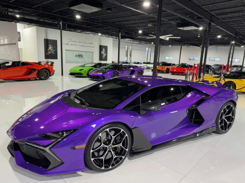 A showroom showcases a striking 2024 Lamborghini Revuelto in purple, with a selection of other colorful sports cars elegantly arranged in the background, inviting enthusiasts to explore and perhaps buy their dream Lamborghini.