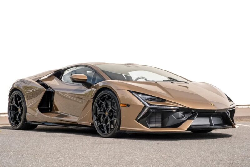 A sleek, bronze exotic car with an angular design, black alloy wheels, and tinted windows is parked on a road against a white background—a true embodiment of luxury. Perfect for high-end enthusiasts exploring exclusive sale listings.